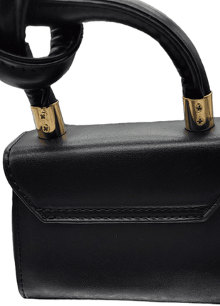 Black leather handbag with a handle featuring metallic gold accents